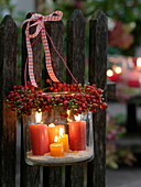 Lanterns with wreath made of roses (rosehip) tied to fence