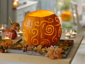 Leuchtender Kürbis (Cucurbita), dekorativ geschnitzt, als herbstliche Tischdek