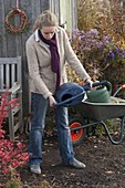 Woman emptying watering can for winter storage