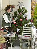 Woman decorates Pinus (pine) for Christmas