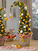 Aus Koniferengrün gesteckte Bäumchen, dekoriert mit Kumquat-Früchten