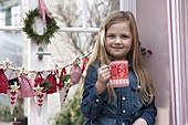 Mädchen mit Adventskalender am Fenster