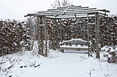 Hölzerner Pavillon mit Bank im verschneiten Garten