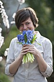 Woman smells bouquet with Hyacinthus hybrid (hyacinths)