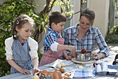 Frau mit Kindern beim Eierfärben