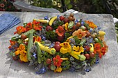 Colourful vegetable wreath with herbs and edible flowers