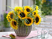 Helianthus annuus (sunflowers) and Panicum (witch grass) in basket vase