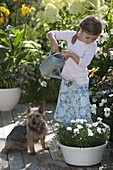 Girl watering bowl with Dianthus (carnations)