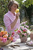 Frau steckt kleinen Strauß mit gemischten Rosa (Rosen) und Anemone