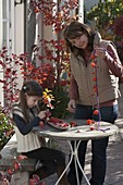 Girl making autumn necklace from physalis (lanterns), pink