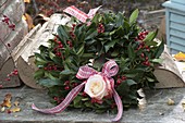 Autumn wreath of Ilex (holly) with red berries and pink (rose)