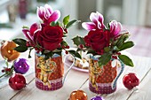 Weihnachtstassen als Vasen mit Rosa (Rosen), Cyclamen