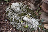 Moosbewachsene Figur aus Zement : schlafendes Kind im Blätterbett