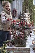 Homemade wicker basket with candles, filled with apples (Malus)