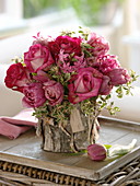 Rosaroter Frühlingsstrauß in mit Rinde verkleideter Vase