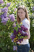 Frau mit duftendem Strauß aus Syringa (Flieder) und Ranunculus acris