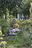 Kleiner Sitzplatz zwischen Beeten mit Stauden und Sommerblumen