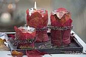 Jam jars with red autumn leaves wrapped as lanterns