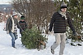 Familie holt Weihnachtsbaum mit dem Schlitten