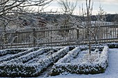 Bauerngarten mit Hecken aus Buxus (Buchs) und Lattenzaun im Schnee