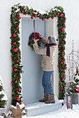 Decorate front door with garland for Christmas