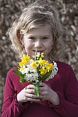 Girl with small spring bouquet of narcissus (daffodils)