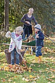 Laub rechen mit Kindern und Hund