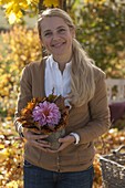 Woman with autumn arrangement of Dahlia (dahlia) and leaves of Acer (maple)