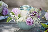 Glas als Windlicht in Müslischale mit Blüten von Rosa (Rosen) und Holunder