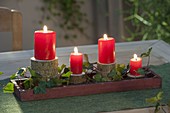 Ungewoehnlicher Adventskranz aus Astscheiben mit roten Kerzen und Hedera