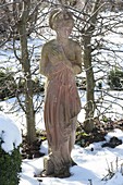 Frauen-Figur aus Terracotta im winterlichen Garten