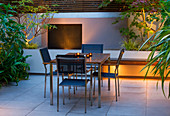 FULHAM Garden DESIGNED by AMIR SCHLEZINGER - MY LANDSCAPES: Minimalist Garden LIT UP at NIGHT - EDGEWORTHIA CHRYSANTHA, Acer ACONITIFOLIUM, TABLE AND CHAIRS, Patio