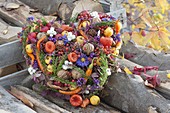 Colorful autumn heart with berries, fruits, nuts, cones, hot peppers