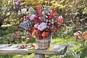 Autumn bouquet with perennials and fruits in basket vase
