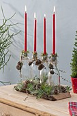 Red stick candles with moss placed on bottles as a candle holder