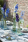 Laid table with delphinium (larkspur) in bottles