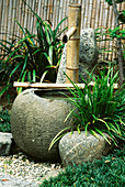 BAMBOO Water PUMP EMPTIES INTO STONE Urn IN THE JAPANESE Garden at THE Huntington BOTANICAL GARDENS, California