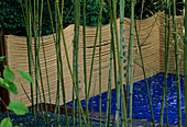 Blauer Glas-Mulch und grüne Murmeln mit Bambus und Seil-Zaun