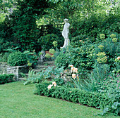 Statue mit Euphorbia characias, Iris (Schwertlilie)