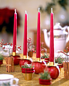 Weihnachtlich geschmückter Tisch mit roten Kerzen auf Äpfeln, Hagebutten in Zimt