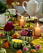 Zierkürbisse als Teelicht und Vase mit Asternblüten, Beeren