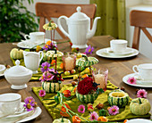 Tischdekoration mit Zierkürbissen als Teelichter und Vasen, Asternblüten,