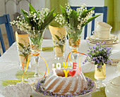 Convallaria (Maiglöckchen) in Weingläsern mit Napfkuchen, Kerzen, aus Buchstaben