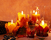 Kerzen in Gläsern umwickelt mit Herbstlaub, Acer (Ahorn), Parthenocissus (Wilder Wein)