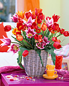 Tulipa (tulip), Vaccinium (blueberry) branches in basket vase