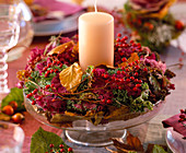 Brassica (Zierkohlkranz), Rosa (Hagebutten), Herbstlaub, Glasschale mit Fuß, Kerze