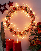 Chain of lights on metal blank as a wreath, red stars and candles, wooden trees, Abi