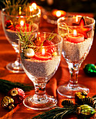 Wine glasses with decorative gravel, tree ornaments, Pinus (pine), red tea lights as lanterns