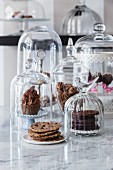 Vegan cookies and cupcakes under glass domes in a café