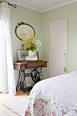 Old sewing machine table in a vintage bedroom with pale green walls